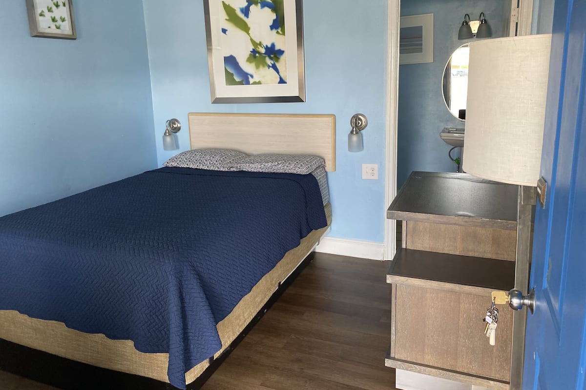 A bedroom with a bed, bedside lamps, a dresser, a mirror, and a framed picture on the wall.
