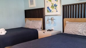 A hotel room with two beds, each with a headboard, a bedside table with a lamp, and a framed picture on the wall. - Howard Johnson by Wyndham Sebring (Sebring)