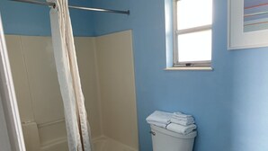 A bathroom with a shower, toilet, and a window. - Howard Johnson by Wyndham Sebring (Sebring)