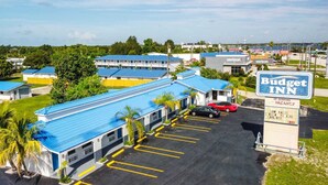A Budget Inn with a blue-roofed building, a parking lot, and a sign indicating low rates and parking availability. - Howard Johnson by Wyndham Sebring (Sebring)