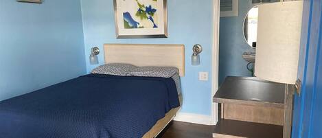 A bedroom with a bed, a dresser, a mirror, and a painting on the wall.