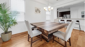 A modern kitchen with white cabinets, a stainless steel refrigerator, and a wooden dining table with four chairs.