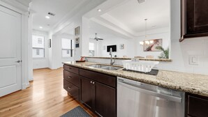 A modern kitchen with a granite countertop, stainless steel appliances, and a dark wood cabinet.
