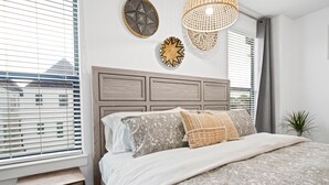 A bedroom with a bed, bedside table, and a window with blinds.