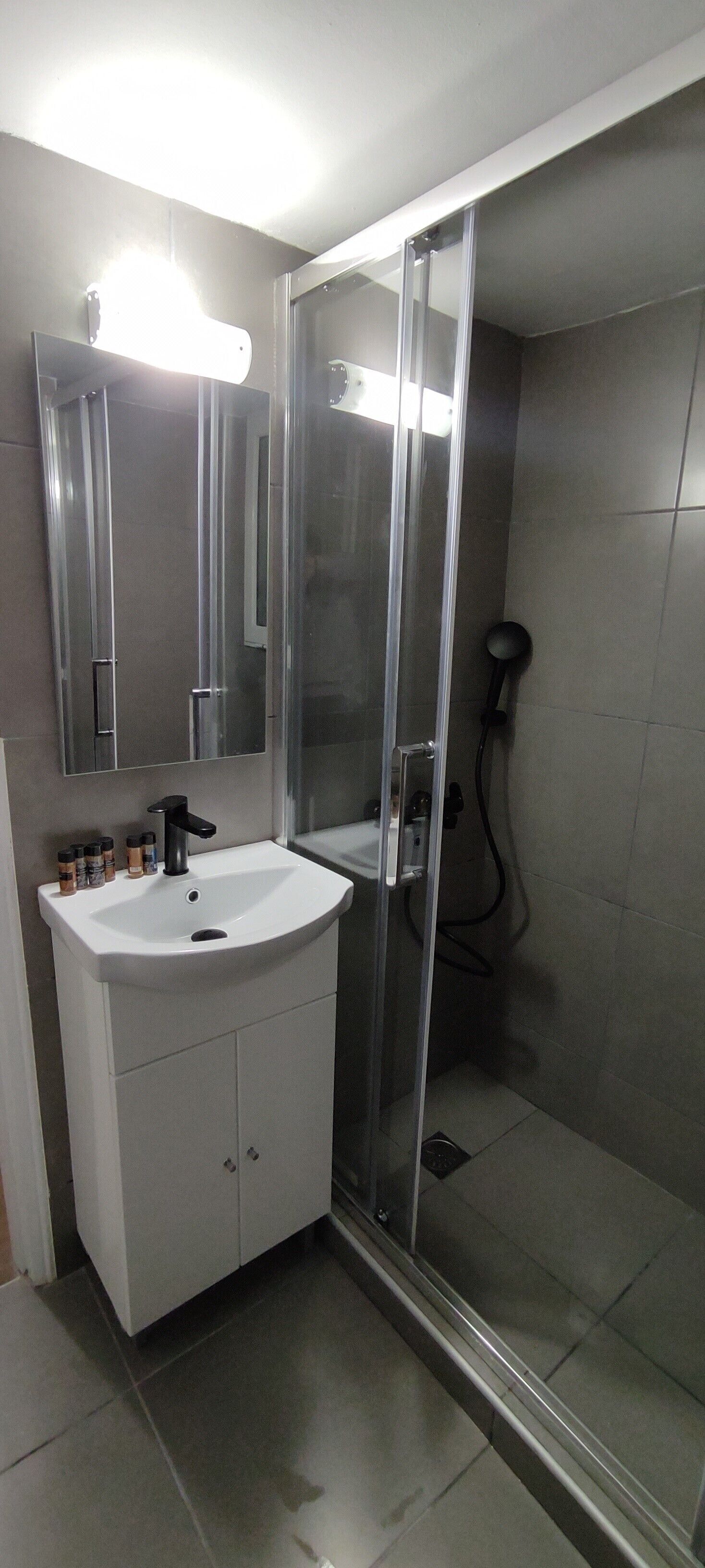 A bathroom with a white sink, a mirror, and a glass-enclosed shower.