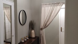 Casa de banho com espelho, um vaso com objetos decorativos e cortina de chuveiro.
