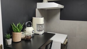 Cozinha com cafeteira, chaleira e uma pequena planta em vaso no balcão.