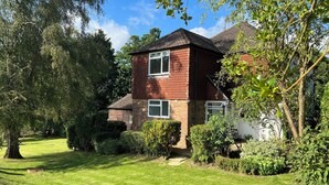 A two-story brick house with a well-maintained lawn and mature trees.