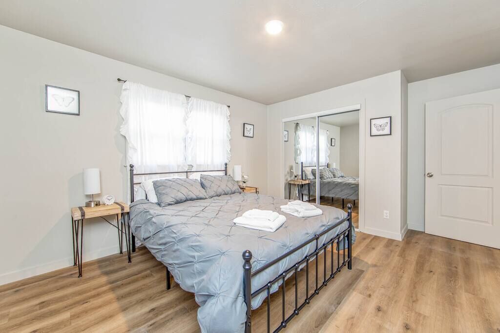 Une chambre à coucher avec un lit, des tables de chevet, un miroir et une porte.