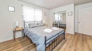 Ein Schlafzimmer mit Bett, Nachttischen, einem Spiegel und einer Tür.