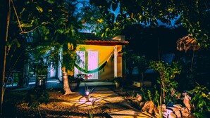 A well-lit house with a hammock, potted plants, and a stone pathway leading to the entrance. - Off grid living! Enjoy and love the Nature! (Savaneta)