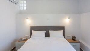 Een hotelkamer met een bed, nachtkastjes, een airconditioning en twee wandlampen.
