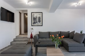 A modern living room with a grey sofa, a coffee table, and a framed artwork on the wall.