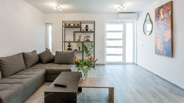 Een moderne woonkamer met een modulaire bank, een salontafel en een decoratieve vaas met bloemen.