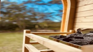 A wooden bench with a metal frame, positioned outdoors with a blurred background of trees and sky. - Feel The Aroha-Love At This Beautiful Beach Haven (MACMASTERS BEACH)