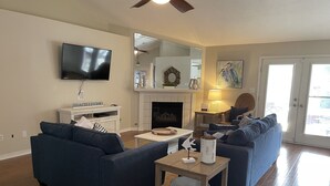 Una sala de estar con dos sofás, un televisor, una chimenea y una mesa de comedor.