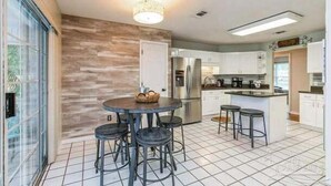 Una cocina moderna con una isla central, taburetes de bar y un refrigerador empotrado.