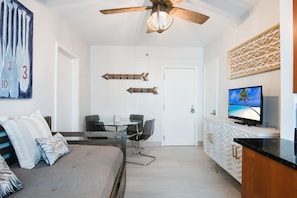 A modern hotel room with a bed, a dining table with chairs, a television, and a ceiling fan. - On Beach, 3rd/Ocean, Pool, SOFI (Miami Beach)