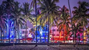 Experience the vibrant atmosphere of OLEVARO HOTEL's beachfront location, surrounded by palm trees and lively shops.