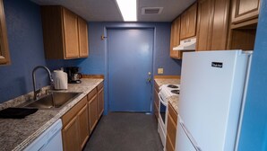 Una cocina compacta con gabinetes de madera, un refrigerador blanco, un lavamanos, una estufa y un microondas.