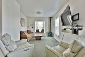 A living room with a sofa, two chairs, a coffee table, a map on the wall, a television, and a fireplace. - 232-Duplex-Private Bathroom-Mountain View (Ashland)