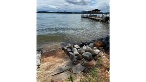 A lakeside view with a dock extending into the water, surrounded by rocks and a grassy area. - Lakeside Retreat Entire House Inground pool, kayaks, dock (Cross Hill)