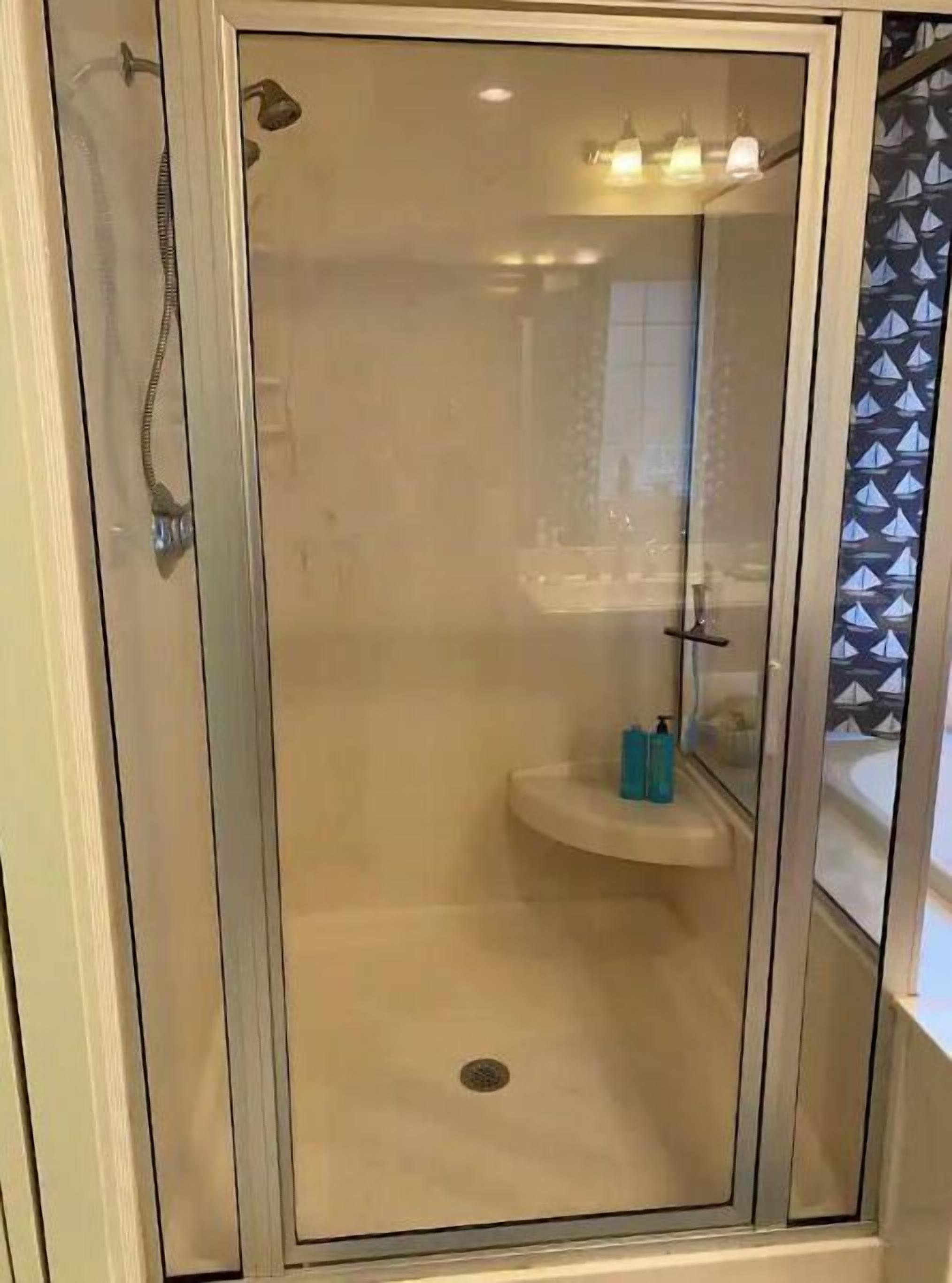 A glass-enclosed shower area with a built-in sink and a mirror.