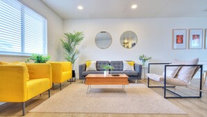 A modern living room with a sofa, armchairs, a coffee table, and a side table.