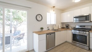 A modern kitchen with a dishwasher, stainless steel appliances, a sink, and a window with blinds.