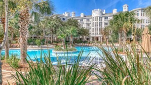 A large pool with a fountain, surrounded by palm trees and a grand hotel building in the background. - Grand Sandestin by Baytowne Wharf Village at Sandestin Golf & Beach Resort.   (Miramar Beach)