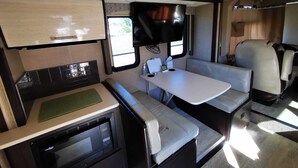 A compact RV interior with a kitchenette, a dining area, and a seating space. - Cozy place in Lake Worth (Lake Worth)