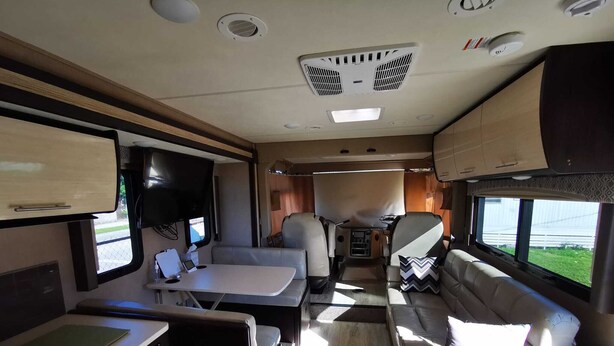 A well-lit RV interior with a dining area, seating, and a kitchen. - Cozy place in Lake Worth (Lake Worth)