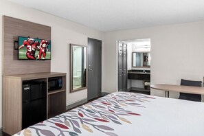 A hotel room with a bed, a TV mounted on the wall, a microwave, a small fridge, a bathroom with a mirror, and a desk with a chair. - Red Roof Inn Richmond - Airport/ Sandston (Sandston)