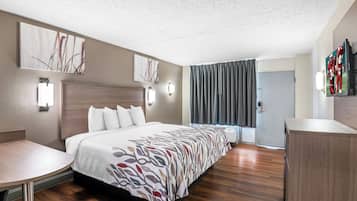 A hotel room with a large bed, a desk, a wardrobe, and artwork on the walls.