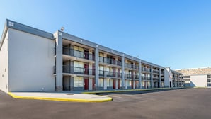 A multi-story motel with a row of balconies, a parking lot, and a clear blue sky. - Red Roof Inn Richmond - Airport/ Sandston (Sandston)