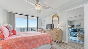 Ett hotellrum med en stor säng, en takfläkt, en tv, en byrå av rotting och utsikt över balkongen.