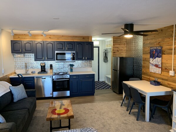 A compact kitchen with dark cabinets, stainless steel appliances, and a wooden accent wall.