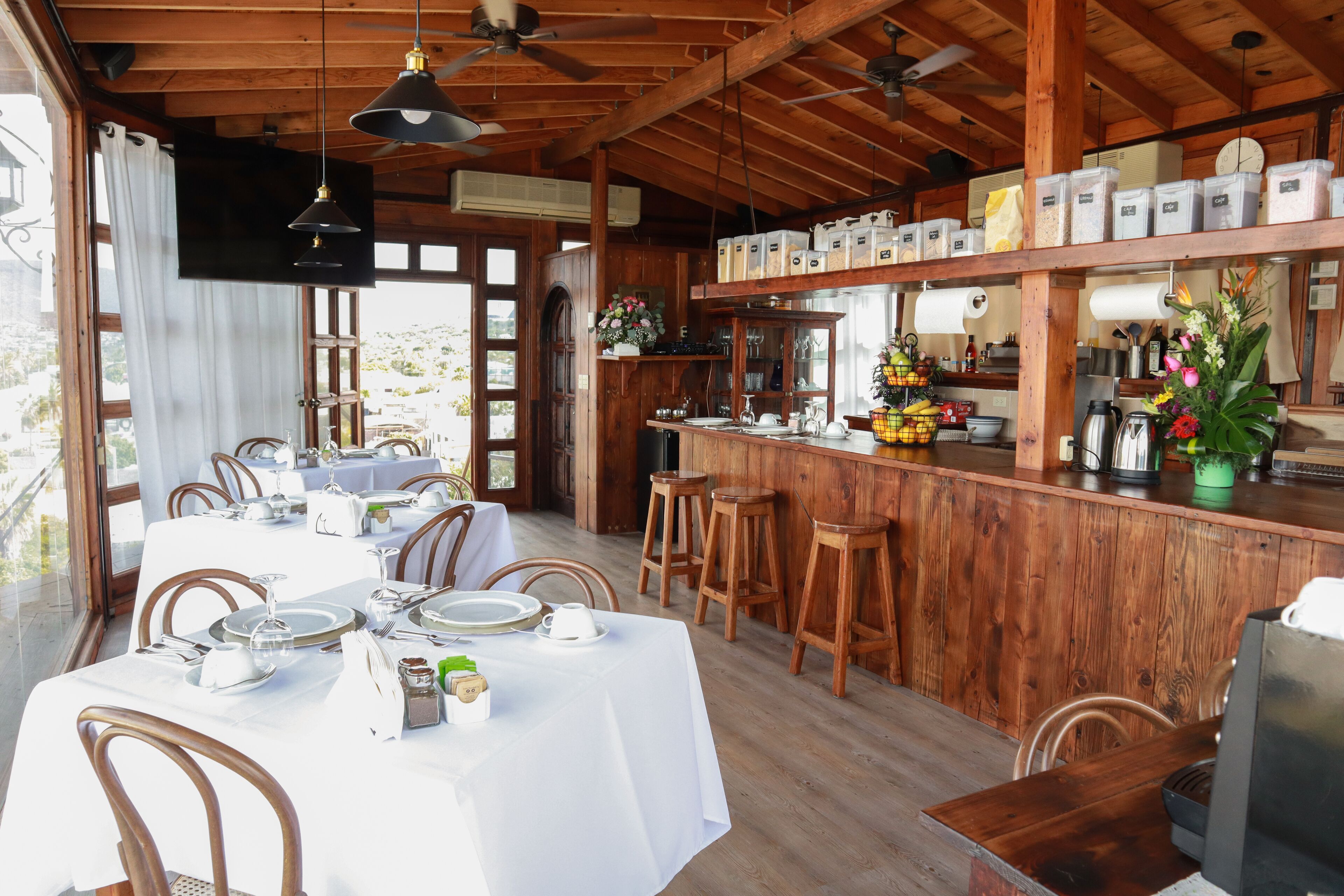 Ein Restaurant mit Holzeinrichtung, weißen Tischdecken und einer Bar.