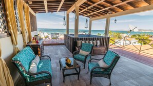 A covered outdoor seating area with wicker furniture, a small table with fruit, and a view of the ocean. - Suite Milena, luxury and comfort close to the malecon. Breakfast included (La Paz)