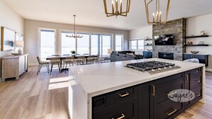 A modern kitchen with a large island, built-in appliances, and a stone accent wall. - 4bed 5bath brand new beach house in Tiny! West Exposure! Sunsets! Hot tub! (Tiny)