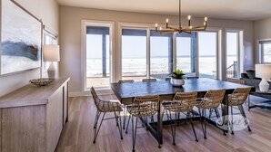 A dining area with a large table, wicker chairs, and a chandelier. - 4bed 5bath brand new beach house in Tiny! West Exposure! Sunsets! Hot tub! (Tiny)