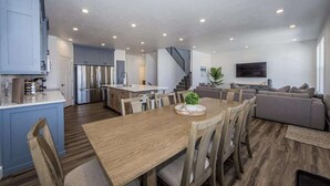 Una cocina moderna con comedor, una escalera y una sala de estar con sofá y televisor.