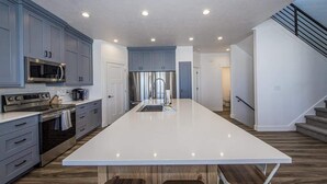 Una cocina moderna con armarios grises, electrodomésticos de acero inoxidable y una isla grande de color blanco.