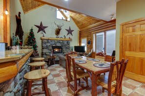 Un intérieur de chalet chaleureux avec une cheminée en pierre, une table à manger en bois et un décor rustique.