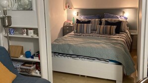 Ein Schlafzimmer mit Bett, Nachttischen, einem Schreibtisch und einer Klimaanlage.