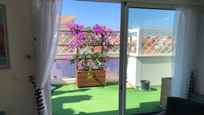 Ein Zimmer mit großem Fenster mit Blick auf eine grüne Rasenfläche und ein Holzpflanzgefäß mit violetten Blumen.