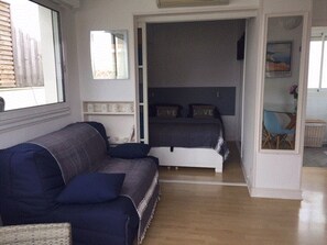 A cozy room with a sofa, a bed, and a small table. - Appartement T2 avec grande terrasse sans vis à vis au centre d'Arcachon (Arcachon)