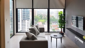 Un soggiorno moderno con un divano, un tavolino rotondo e un'ampia finestra che offre vista sulla città.