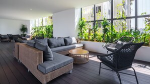 Un'ampia zona interna con un divano spazioso, un tavolo rotondo e una sedia in vimini.