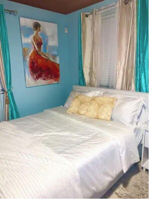 Cozy retreat with a single bed, light blue walls, and a beautiful painting.